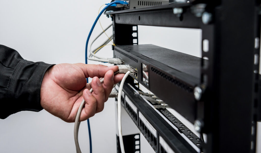 Technician connecting network cables to switches. Connecting cables